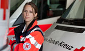 Foto: Rettungssanitäterin zischen DRK-Wagen.
